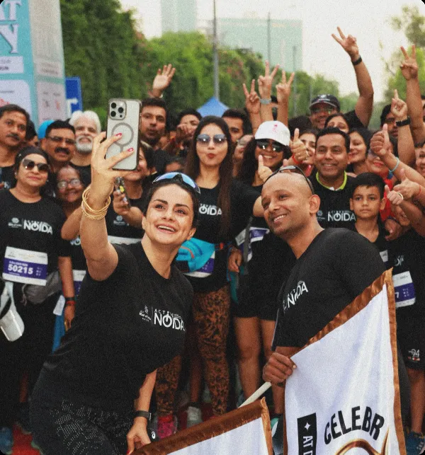 An Indian celebrity holding her phone for a selfie with a large crowd gathered behind her. 